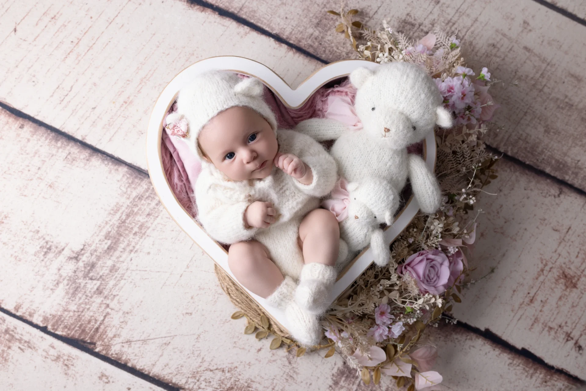 Photographie de naissance, la maman tient dans ses bras son bébé et lui fait un bisou sur le front