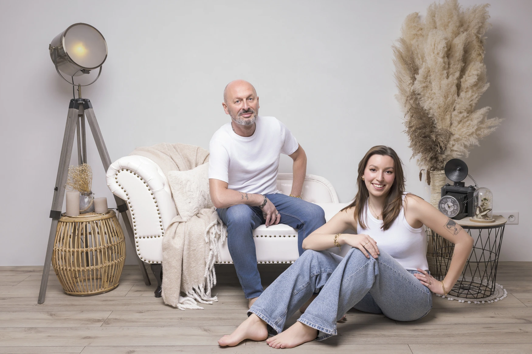 Photographie d'une petite fille avec une petite robe blanche et un bandeau à fleur, assises dans une chaise haute en rotin, dans un décor bohème, photo capturée par Del'Clic Studio, photographe située à abancourt proche de cambrai, arleux, paillencourt, brunémont, aubigny, cantin, féchain, aniche, somain, Nord-Pas-de-Calais