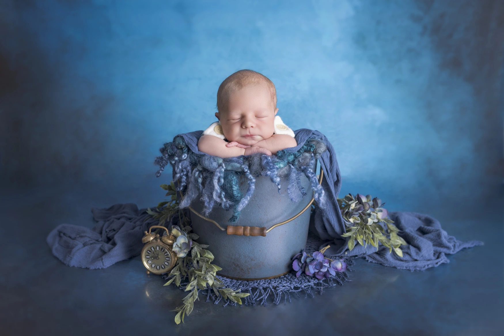 Photographie de naissance, la maman tient dans ses bras son bébé et lui fait un bisou sur le front