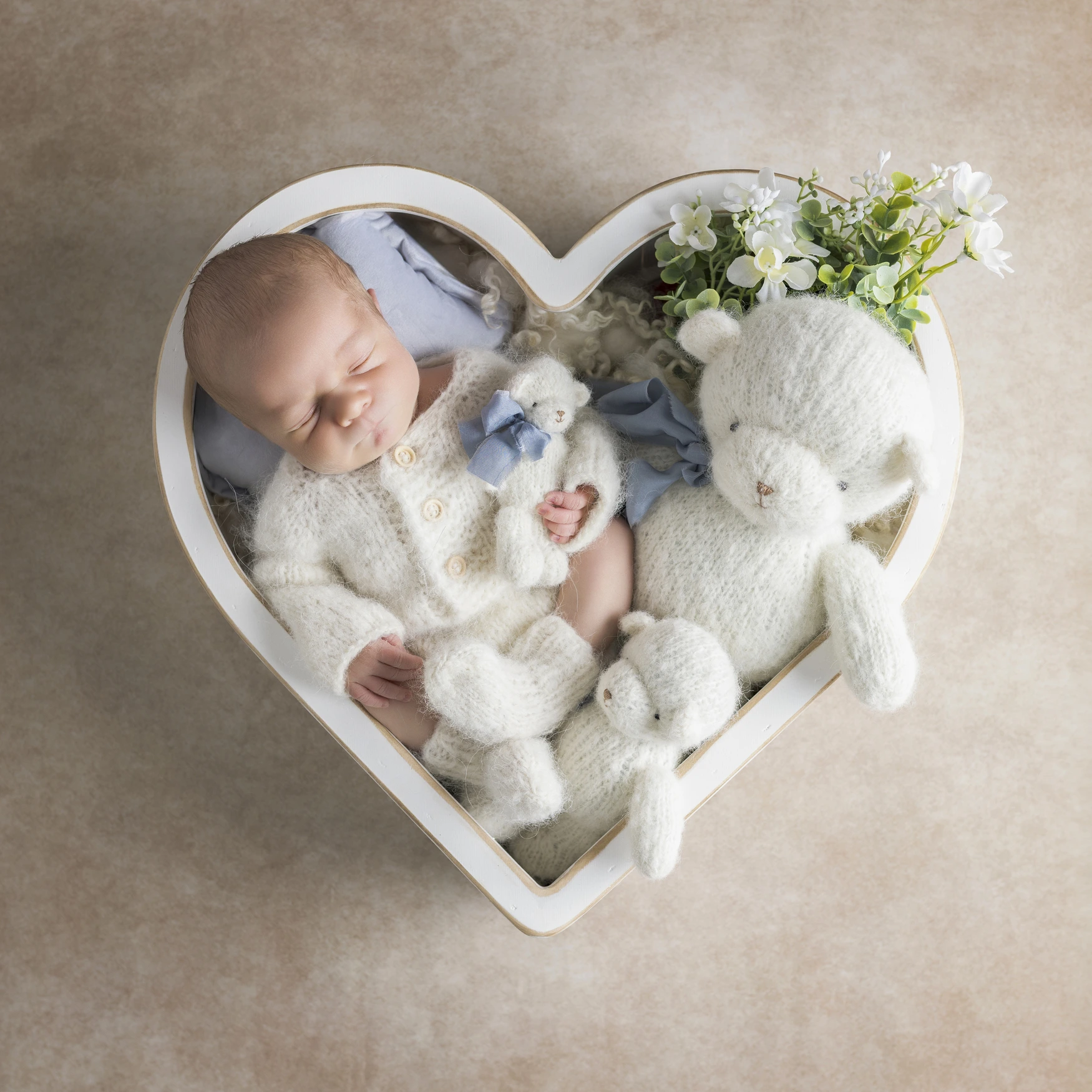 Photographie de naissance, la maman tient dans ses bras son bébé et lui fait un bisou sur le front