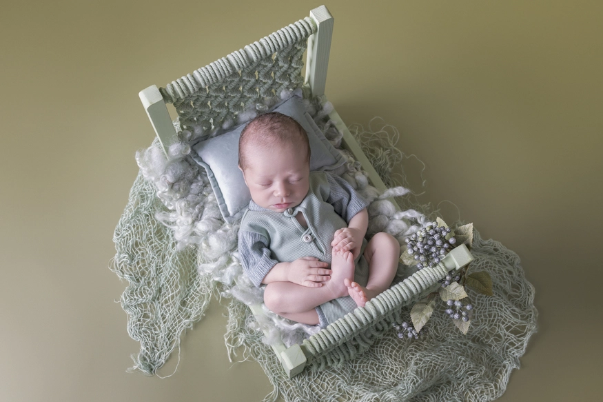 Photographie de naissance, la maman tient dans ses bras son bébé et lui fait un bisou sur le front