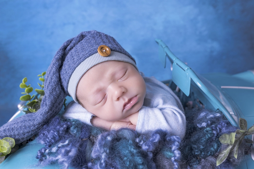 Photographie de naissance, la maman tient dans ses bras son bébé et lui fait un bisou sur le front