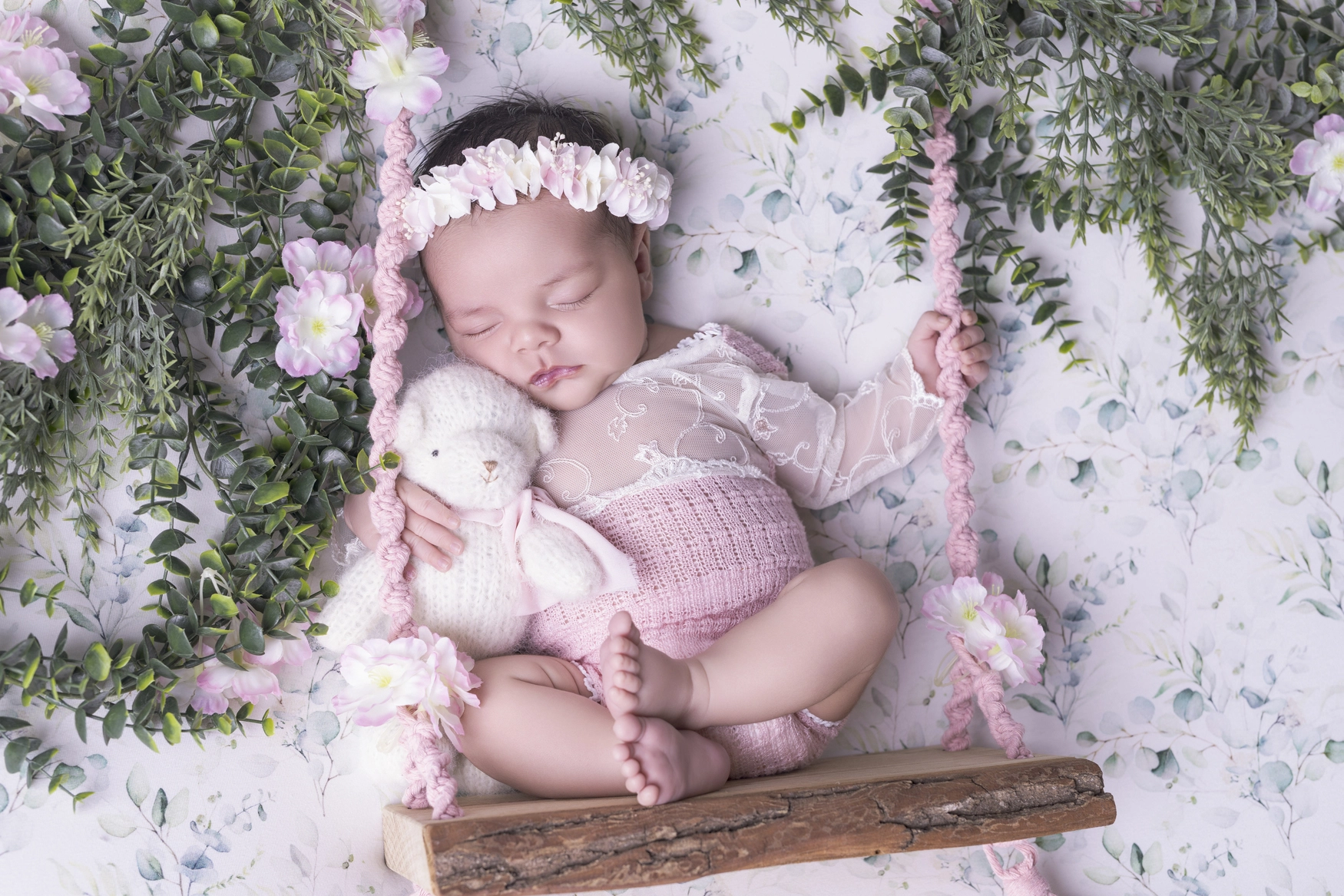 Photographie de naissance, la maman tient dans ses bras son bébé et lui fait un bisou sur le front