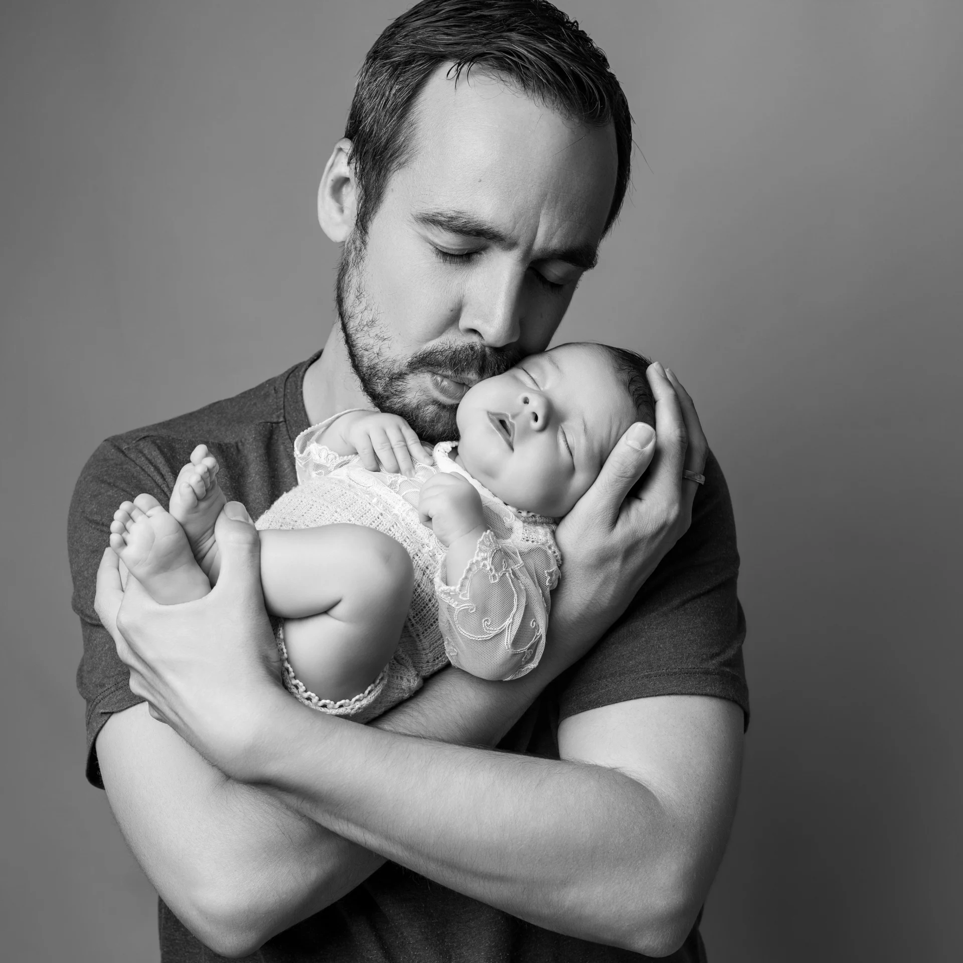Photographie de naissance, la maman tient dans ses bras son bébé et lui fait un bisou sur le front