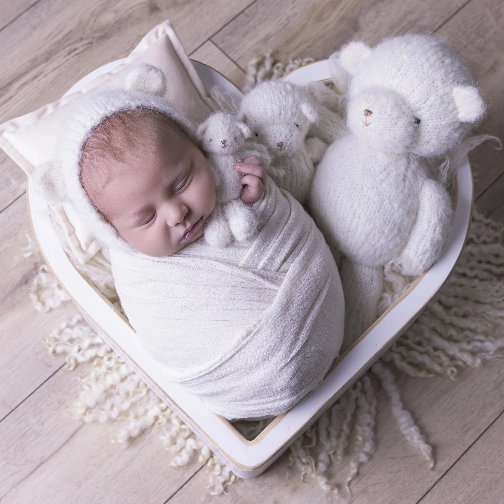 Photographie de naissance, la maman tient dans ses bras son bébé et lui fait un bisou sur le front