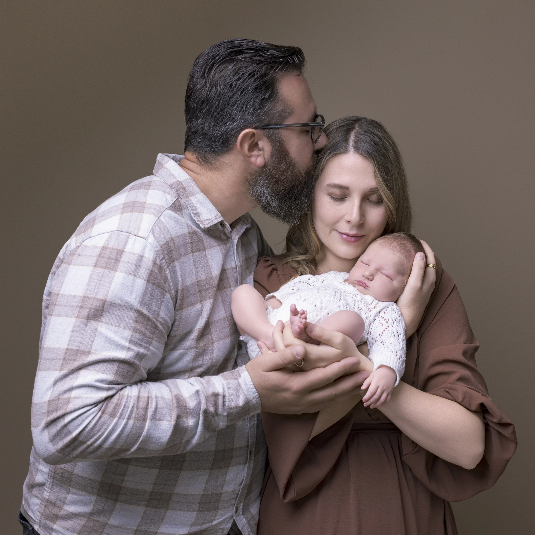Photographie de naissance, la maman tient dans ses bras son bébé et lui fait un bisou sur le front