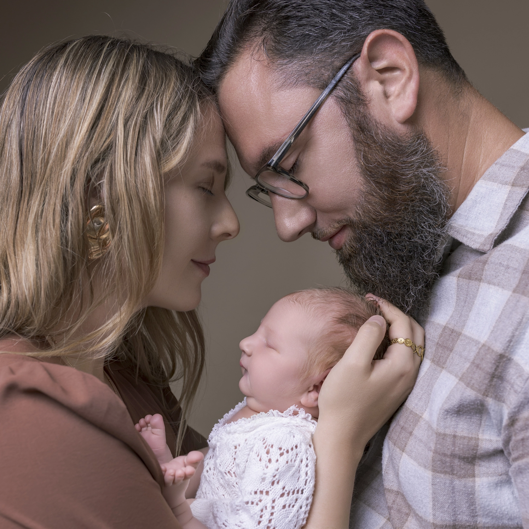 Photographie de naissance, la maman tient dans ses bras son bébé et lui fait un bisou sur le front