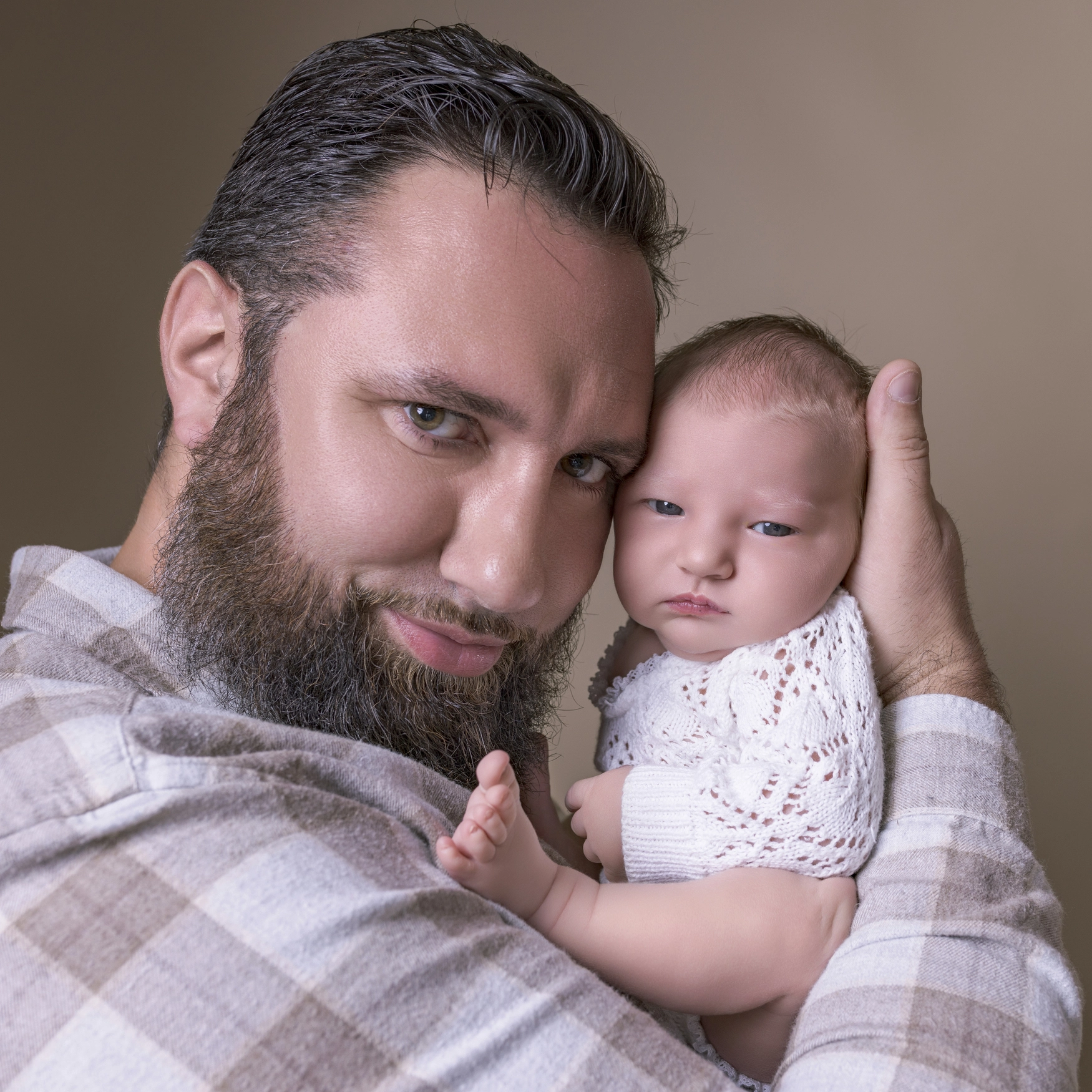 Photographie de naissance, la maman tient dans ses bras son bébé et lui fait un bisou sur le front